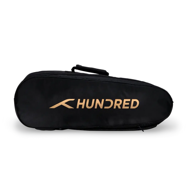 HUNDRED Cosmogear Kit Bag, a black elongated sports bag with a smooth finish, gold logo, and top carry handle