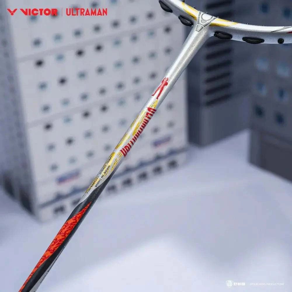 Badminton racket from the VICTOR X ULTRAMAN Collection, with a silver shaft, red and yellow graphics, and black accents