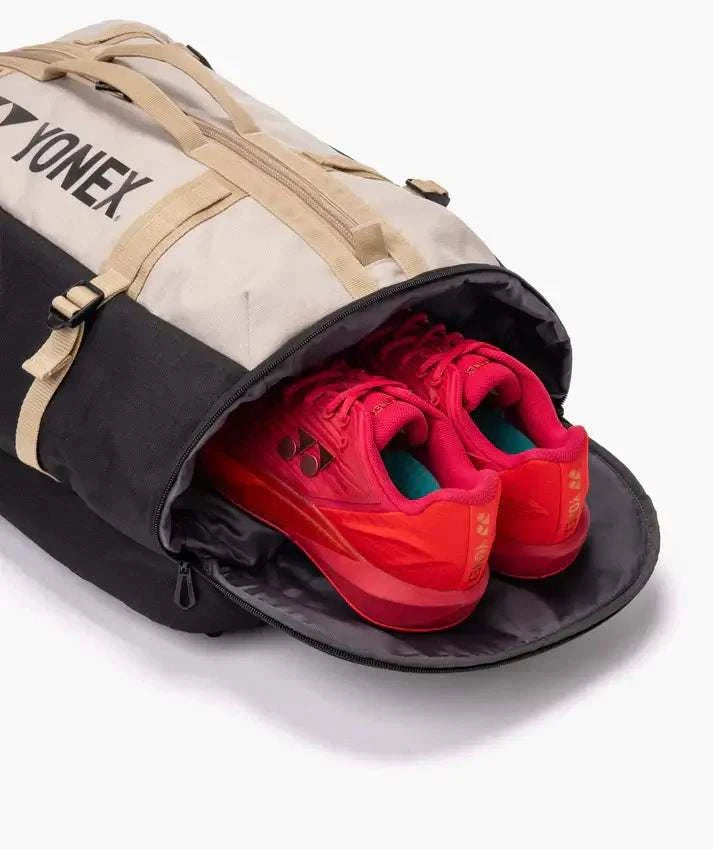Yonex GEARLOGIC Backpack in beige and black with a wide-open shoe compartment holding bright red athletic shoes