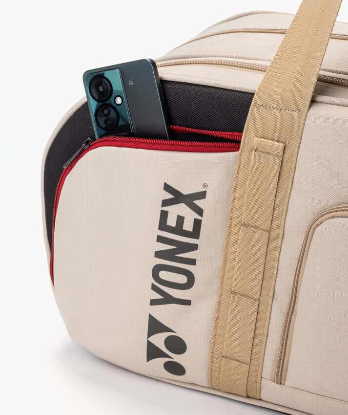 Yonex GEARLOGIC Tournament Bag in beige fabric with a red-trimmed front pocket, black logo and wide shoulder strap
