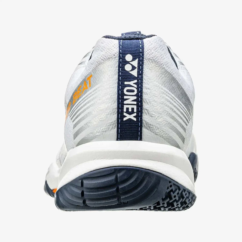 Yonex Strider Beat Power Cushion badminton shoe in white synthetic mesh with gray accents, orange lettering and a navy heel tab