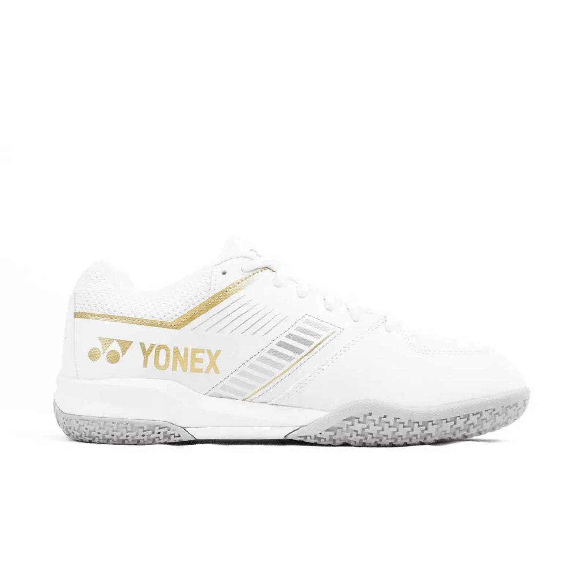 Yonex Strider Flow badminton shoe in white synthetic material with gold logo and trim, textured gray rubber sole