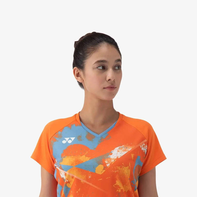Yonex Women's Crew Neck Shirt in bright orange polyester with a blue V-neck and abstract multicolour graphics